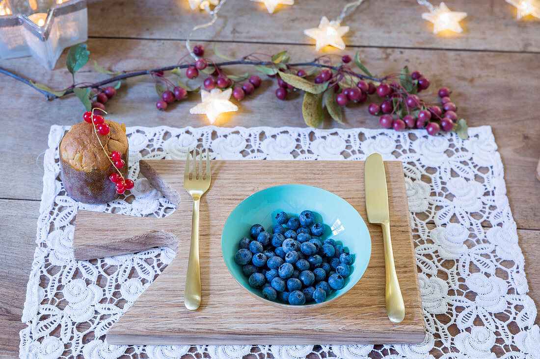 Bowl of blueberries and gold cutlery on lacy place mat