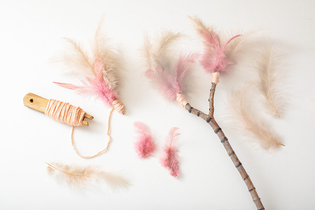 Tying feathers to twig with woollen yarn