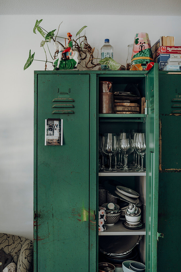 Old green locker used as cupboard with glasses and crockery