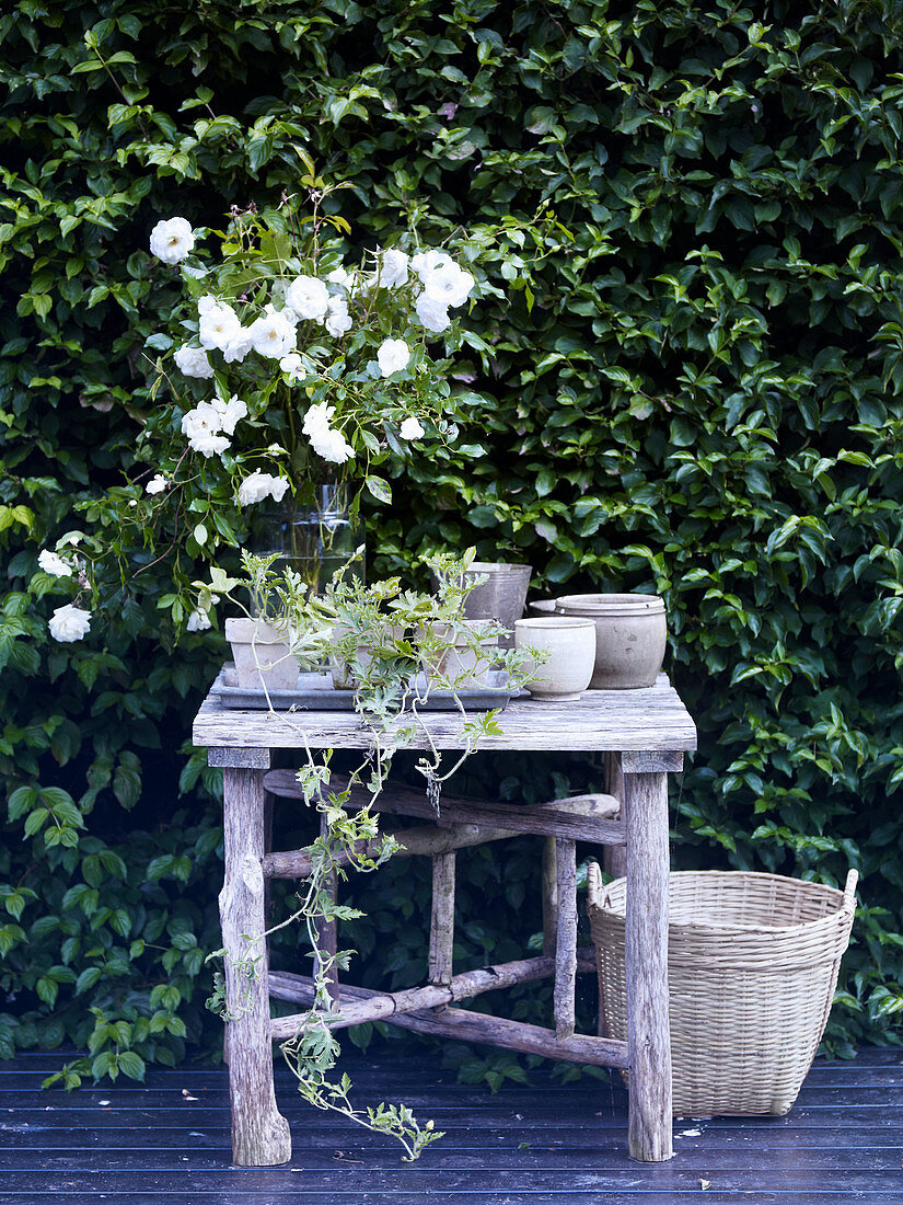 Weißer Strauß aus Rosen auf rustikalem Gartentisch