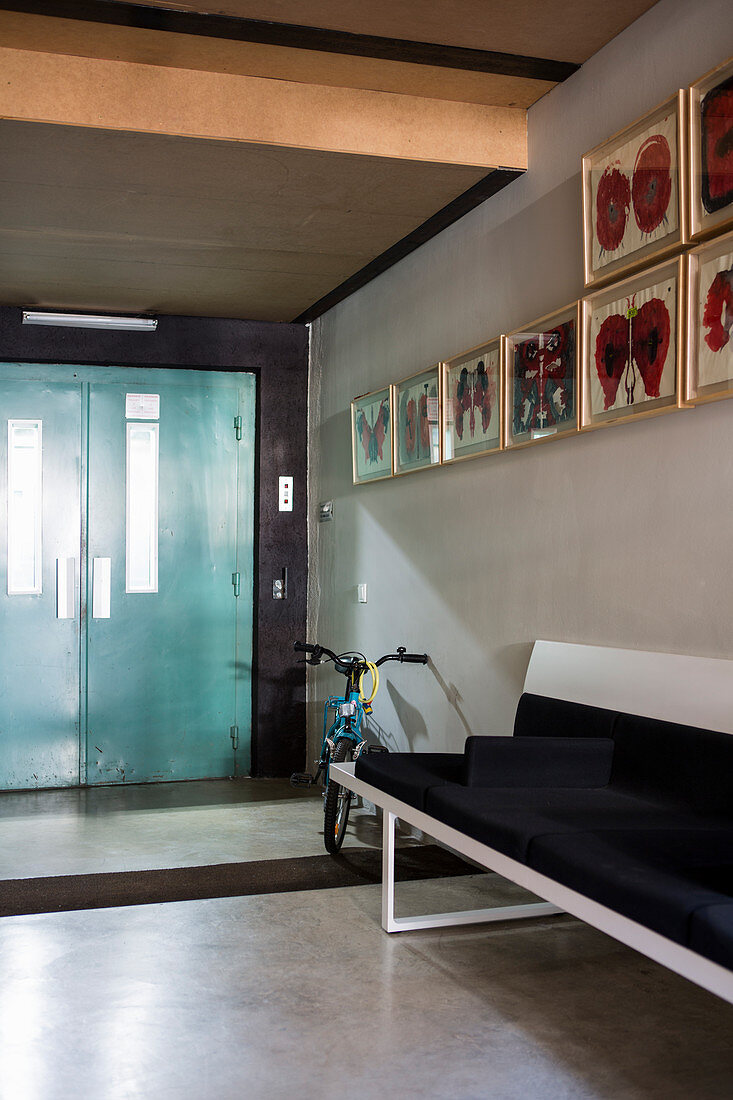 Sitzbank, Fahrrad und Bildergalerie auf Flur mit Betonboden