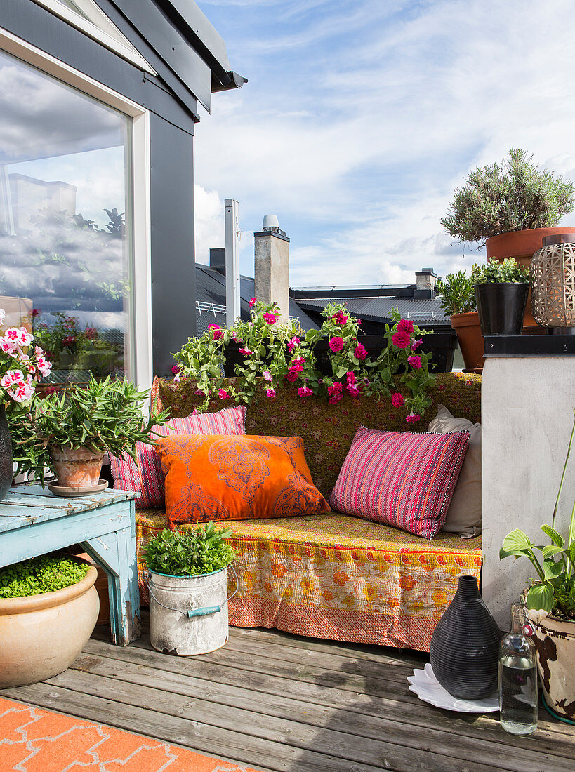 Colourful blanket and cushions on bench on roof terrace