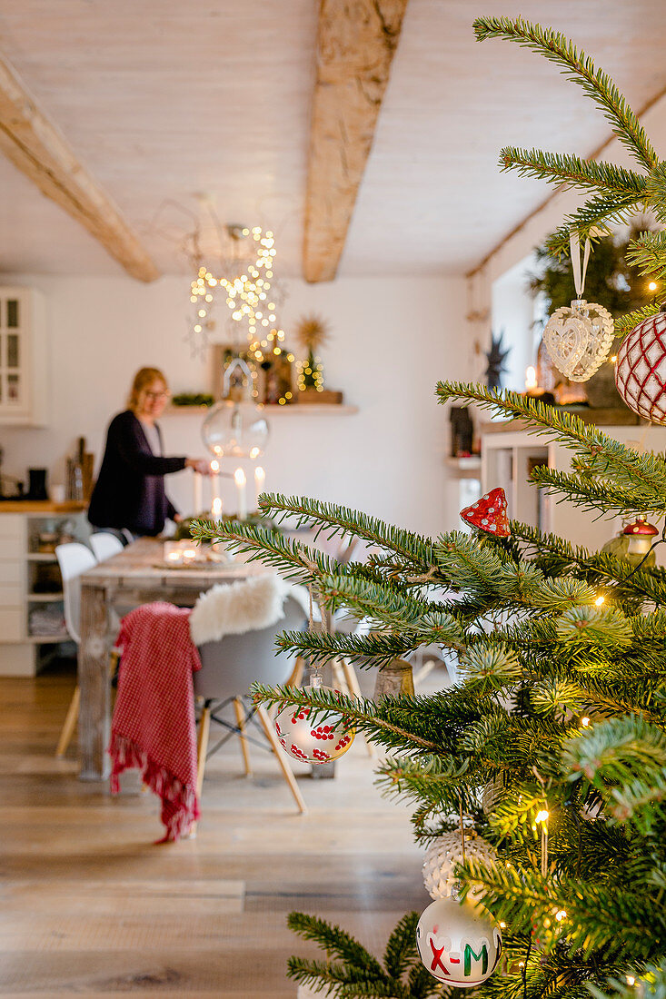Frau am Esstisch im weihnachtlich dekorierten Wohnraum