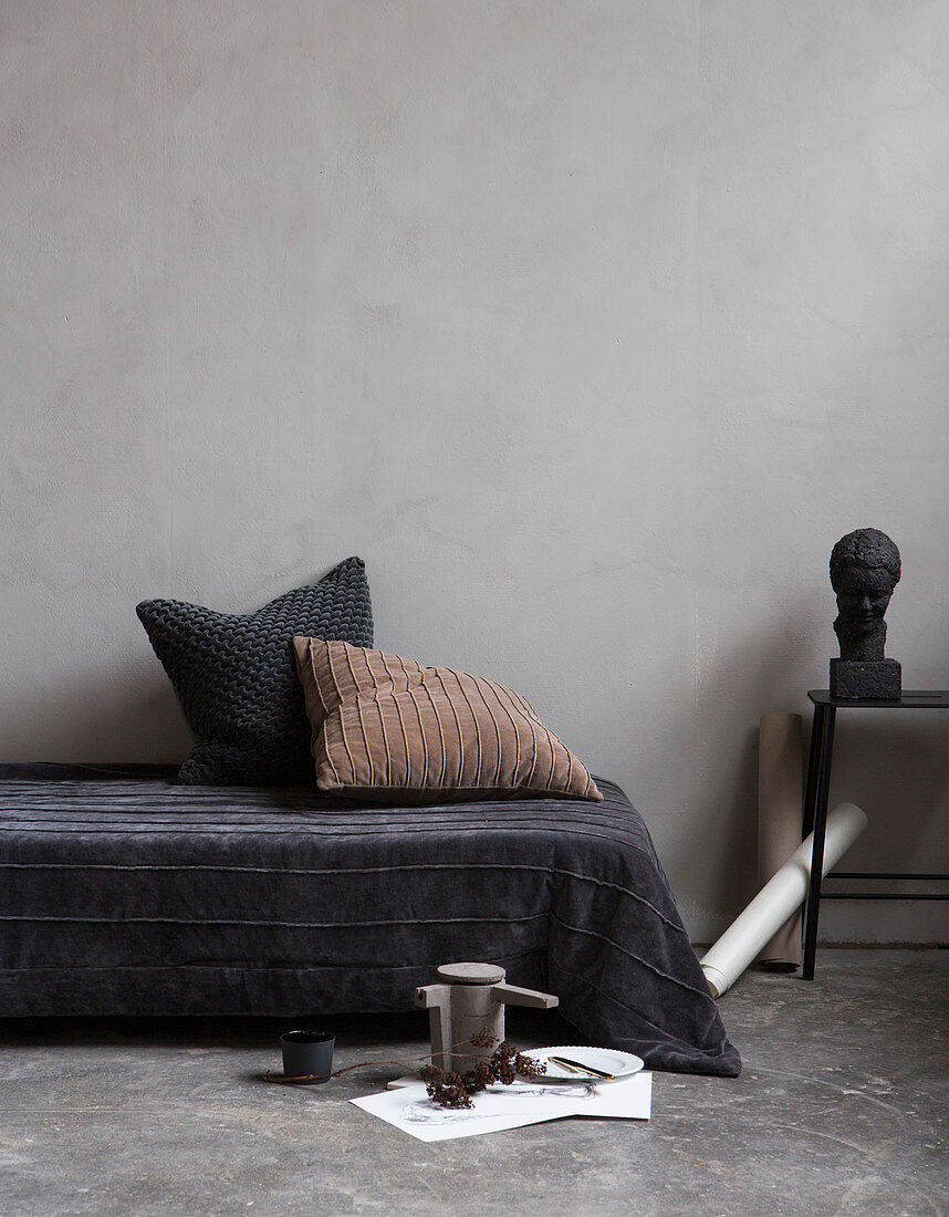 Velvet blanket and structured scatter cushions on couch on concrete floor