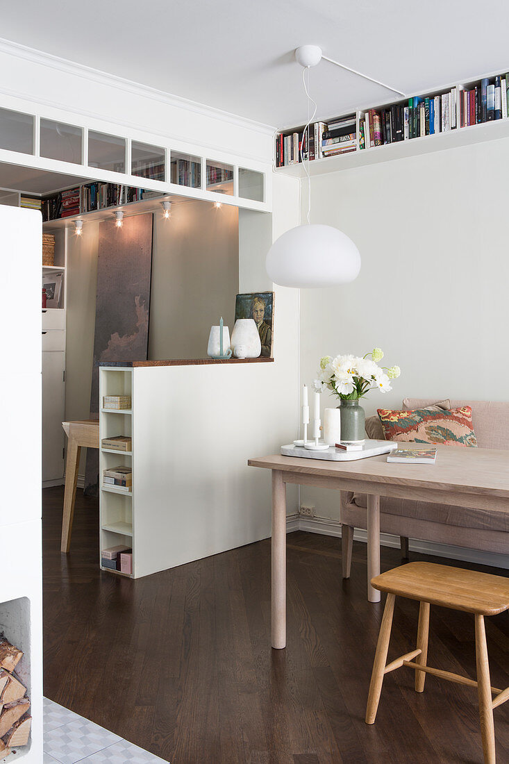 Dining table next to open doorway with half-height partition wall in apartment interior
