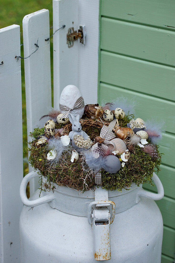 Easter nest with Easter bunny, Easter eggs and feathers on old milk churn