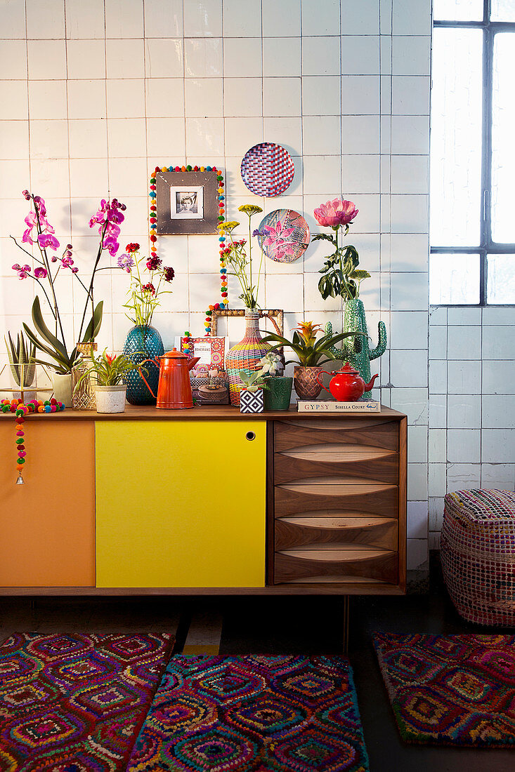 Various vases, cut flowers and houseplants on retro sideboard