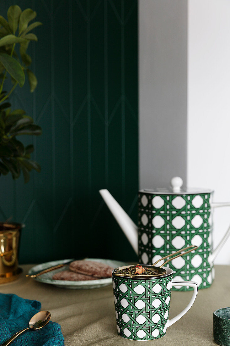 Tasse und Teekanne mit grünem Geflecht-Muster auf dem Tisch
