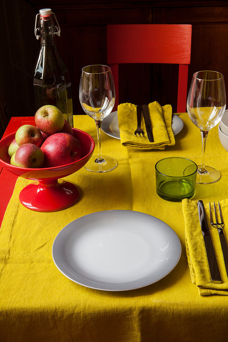 Schale mit Äpfeln auf dem gedeckten Tisch mit gelbem Läufer