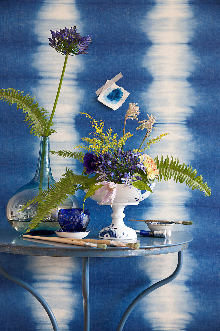 Arrangement of agapanthus and ferns in front of wall with blue ikat pattern