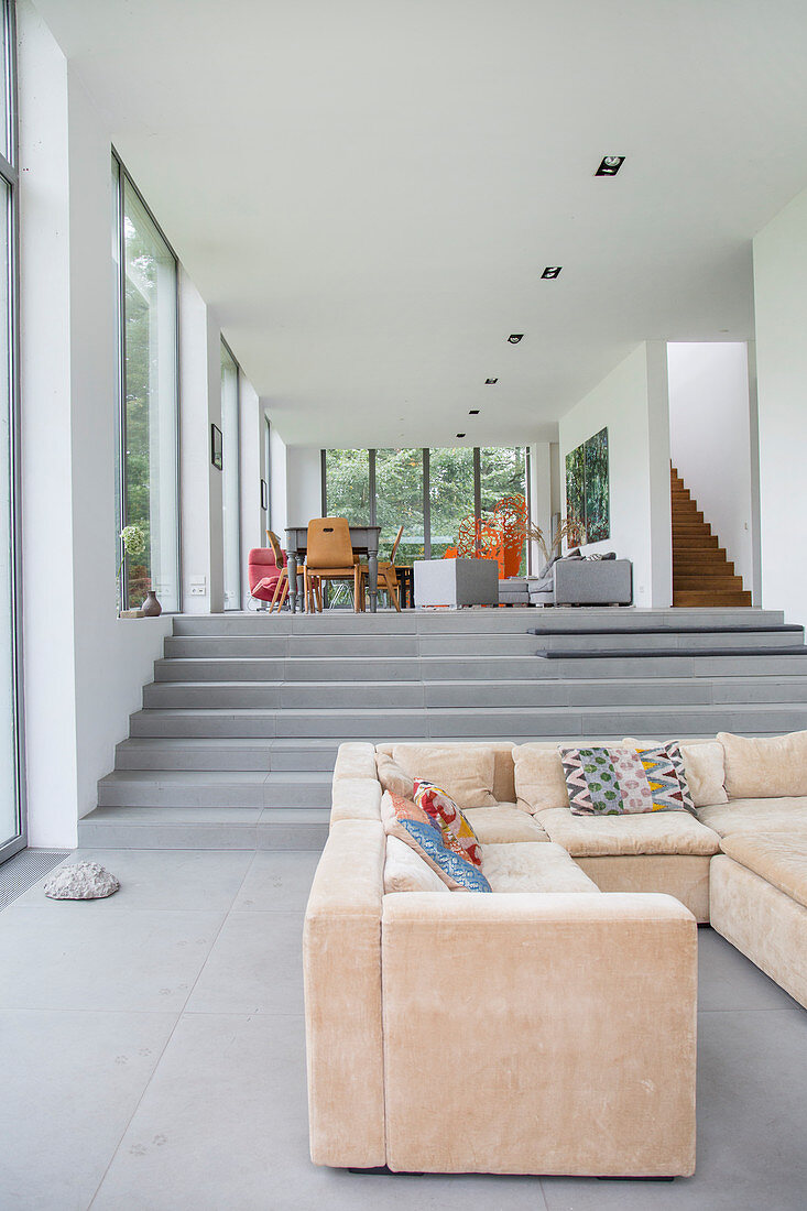 Beiges Sofa im offenen Wohnraum auf mehreren Ebenen