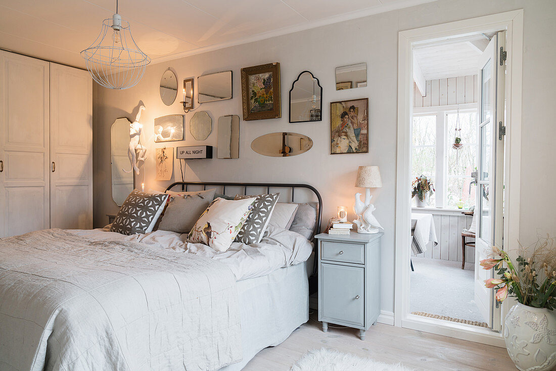 Collection of mirrors above bed in vintage-style, white bedroom