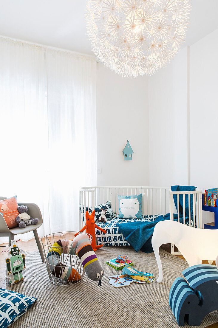Lichtdurchflutetes Kinderzimmer mit Gitterbett und farbenfrohen Spielsachen