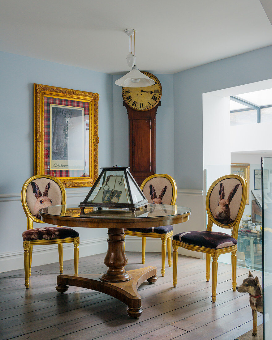 Yellow Baroque chairs with animal motifs on backrests around antique pedestal table