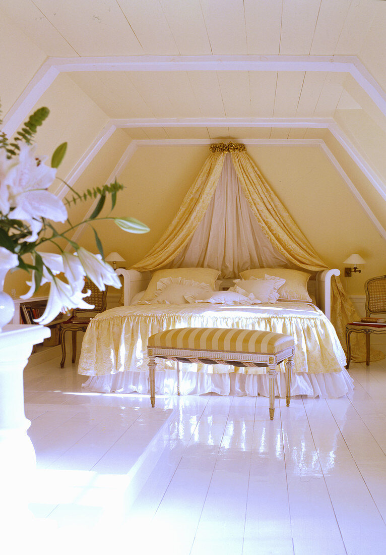 Opulent bed with canopy and ruffles in attic room