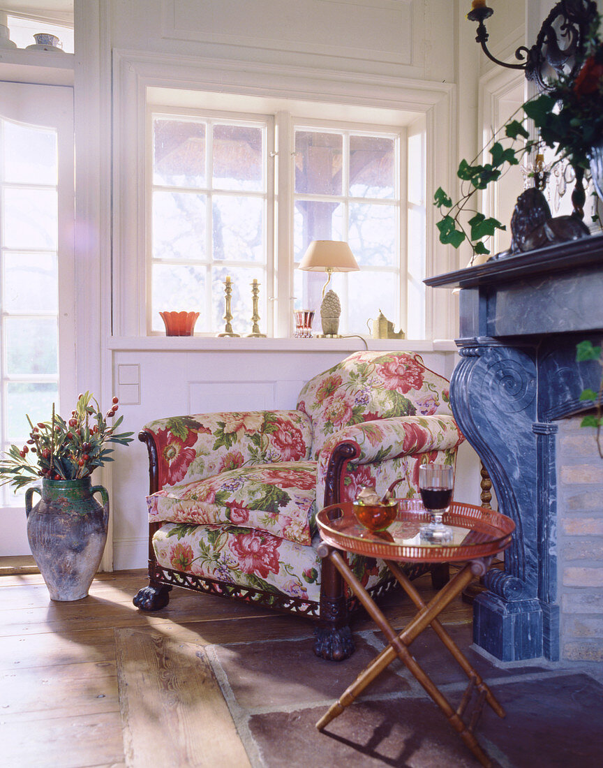 Floral armchair between open fireplace and lattice window