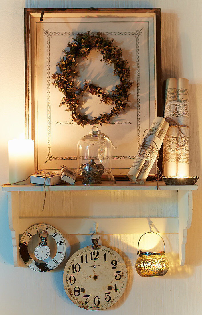Vintage-style, candle-lit, still-life arrangement on wall-mounted shelf