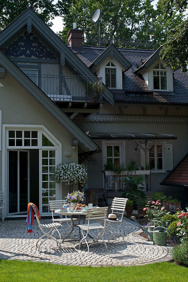 Gartentisch auf gepflasterter Terrasse vorm ländlichen Haus