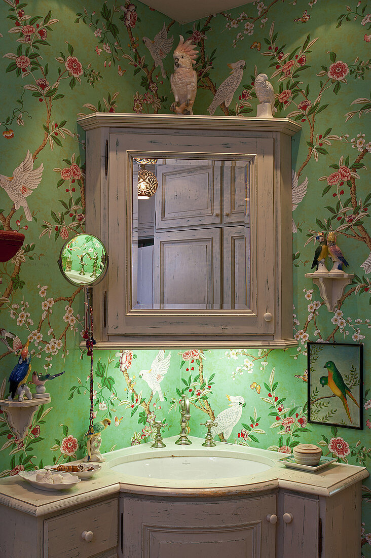 Corner washstand and wall unit in bathroom with floral wallpaper
