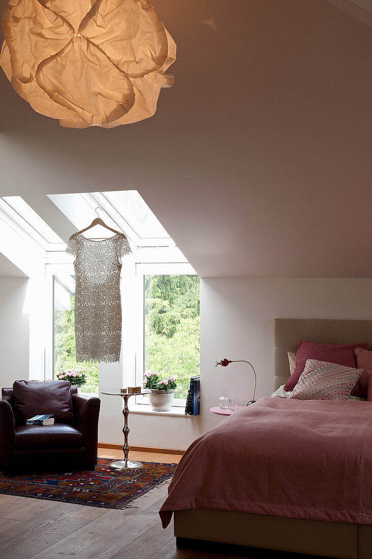 Armchair below skylights in bedroom with sloping ceiling