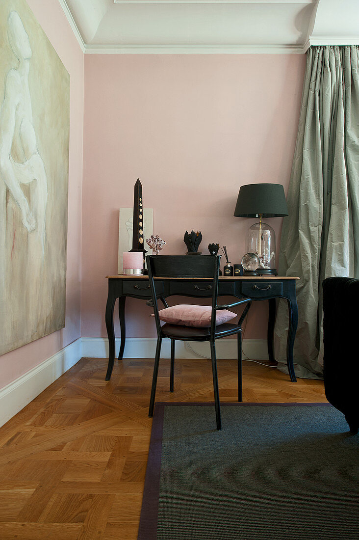 Black chair at Baroque console table against pink wall