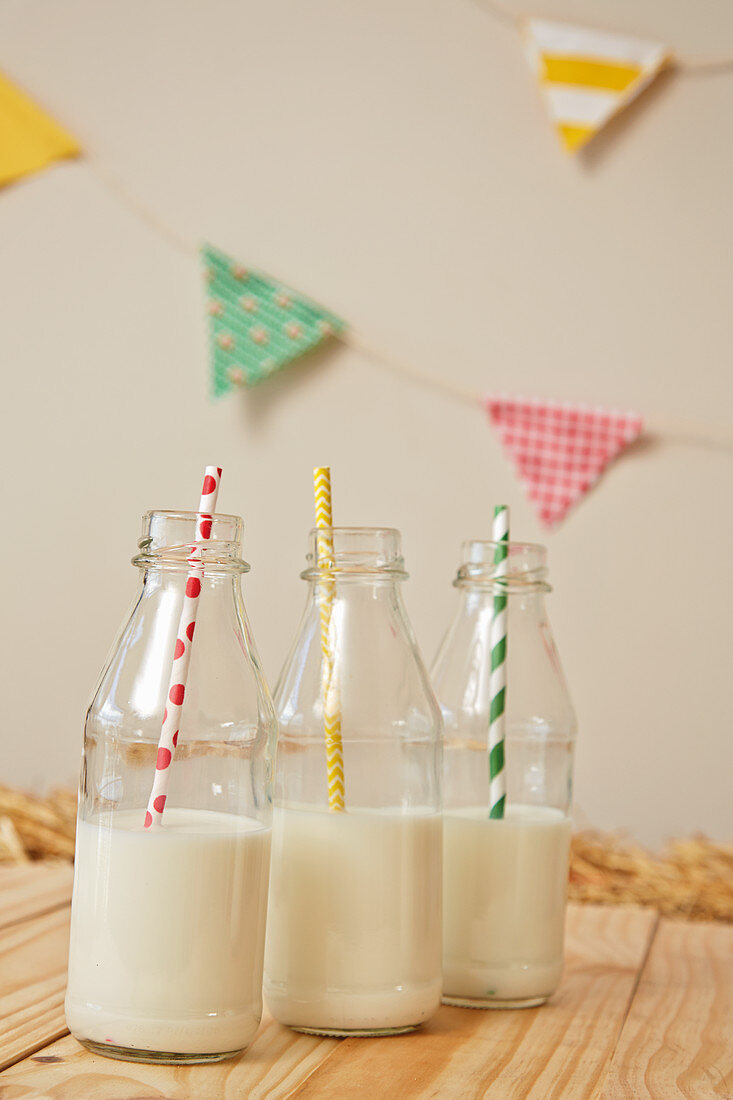 Milch mit Strohhalm in Glasflaschen