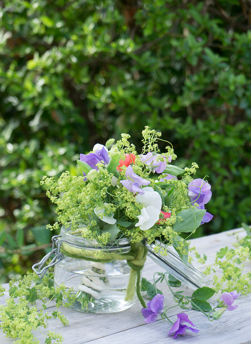 Bouquet of sweet peas and lady's mantle in a mason jar