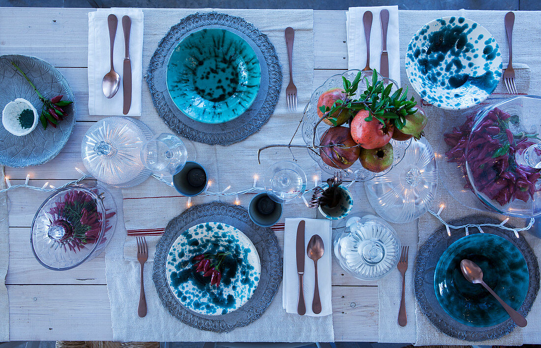Blue-and-white speckled crockery and fairy lights on festively set table