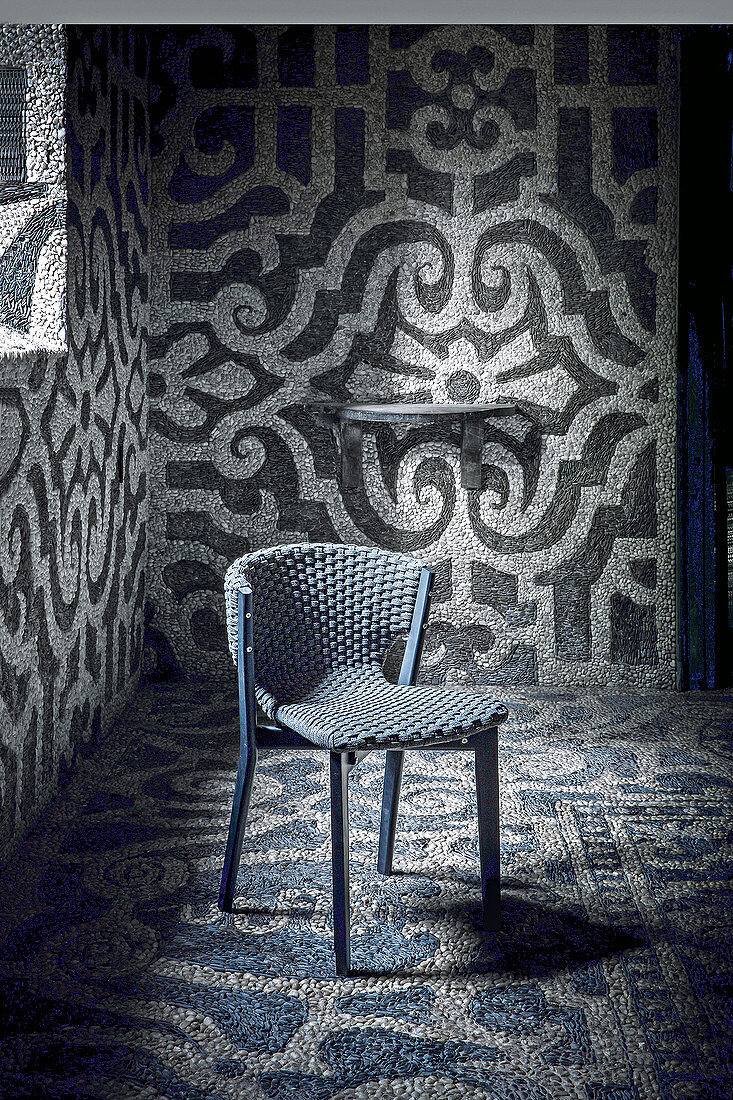 Schwarzer Mahagoni-Holzstuhl mit Flechtbespannung in Raum mit Mosaikwänden und -boden
