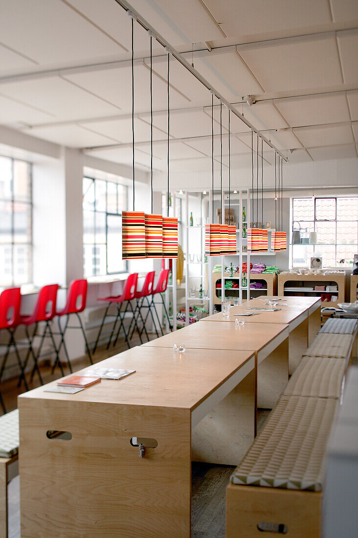 Custom tables and benches below pendant lamps in loft-style cafe