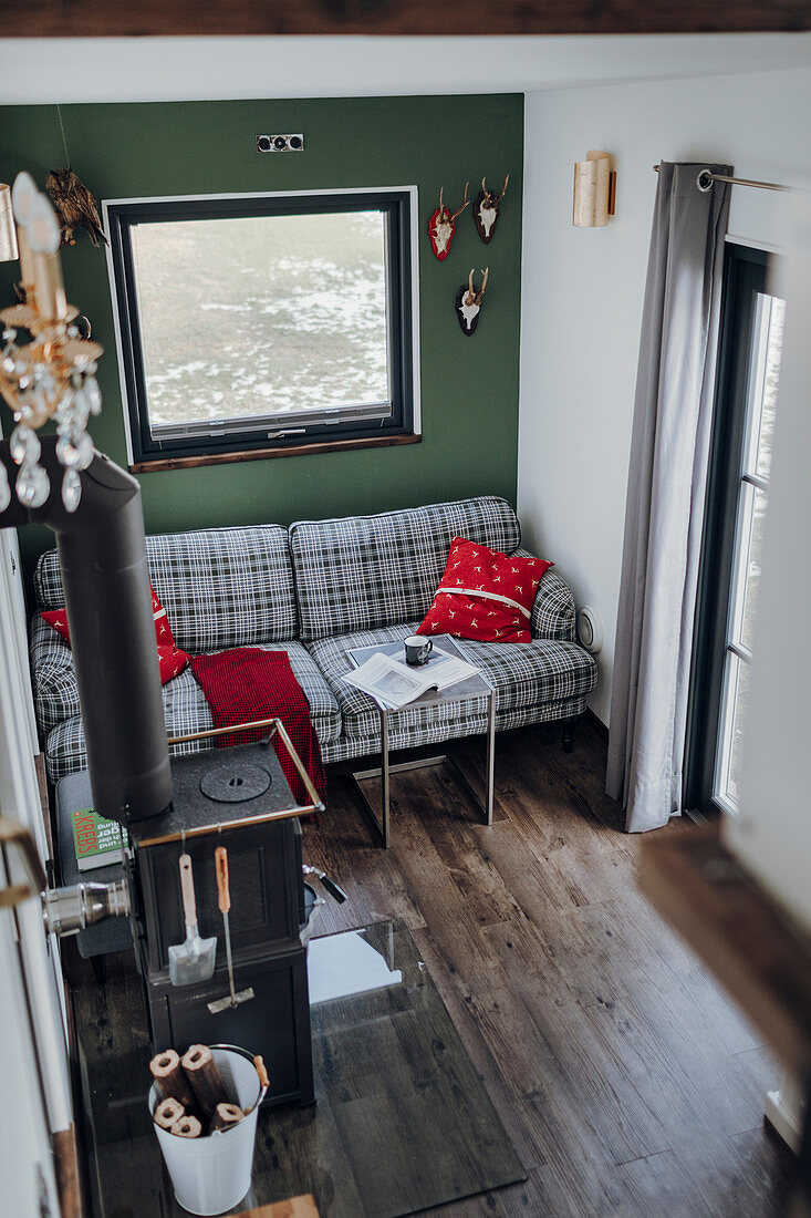 Tartan sofa against green wall and wood-burning stove in tiny house