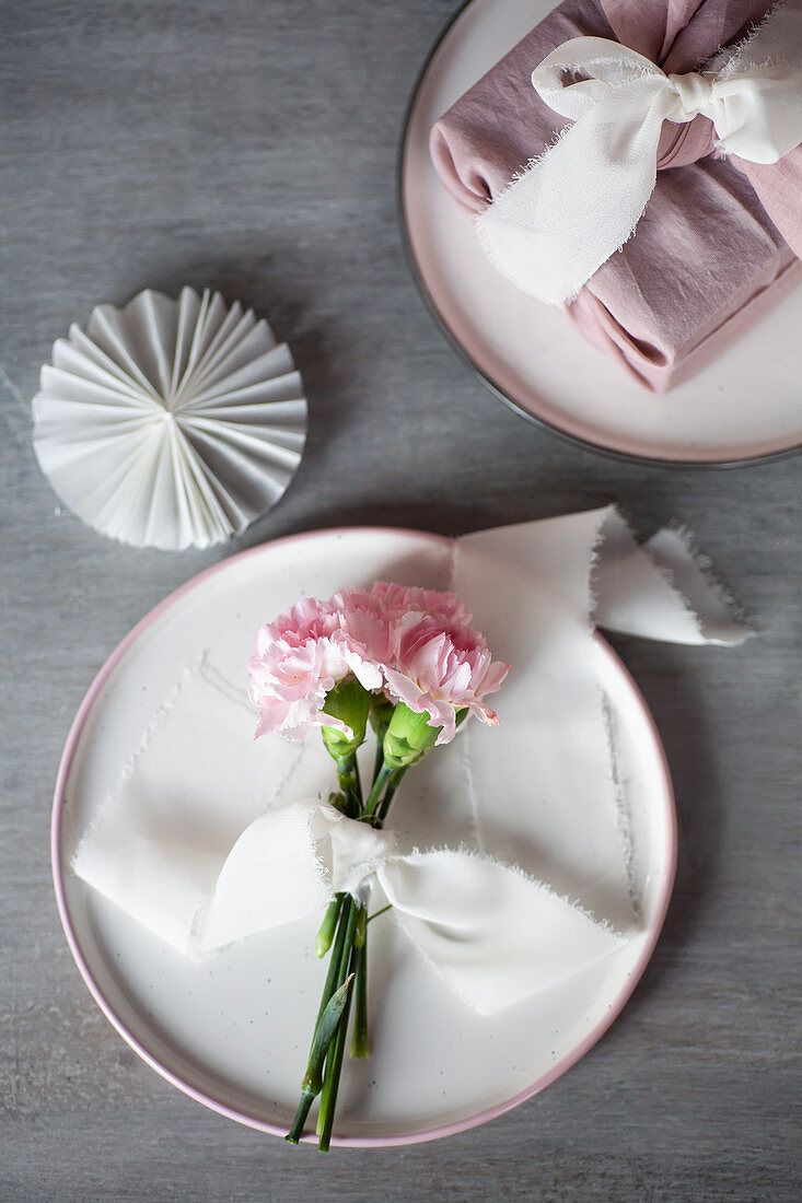 Pastel arrangement: pink carnations tied with ribbon on plate