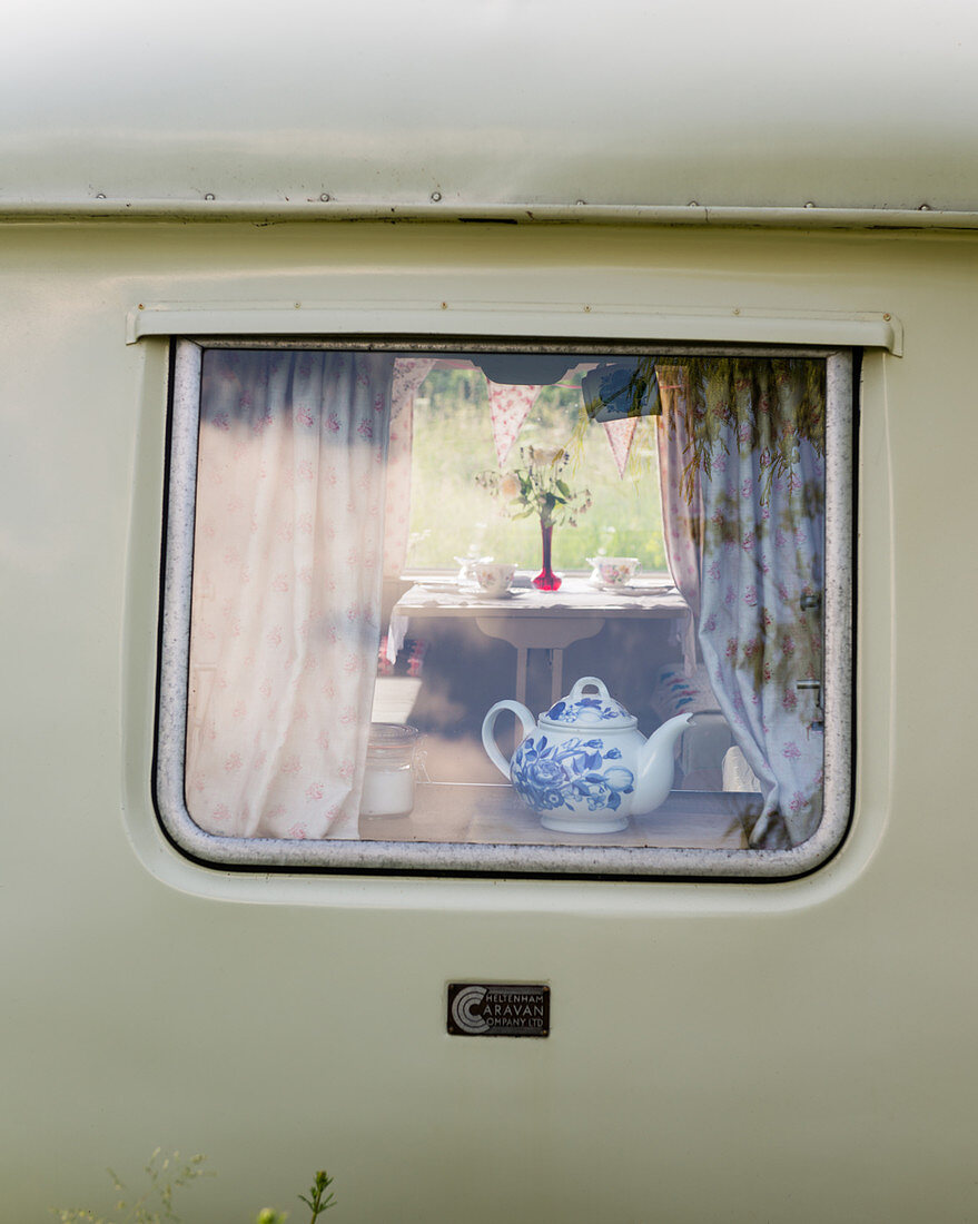 Blick durchs Fenster in einen alten Wohnwagen mit nostalgischer Deko