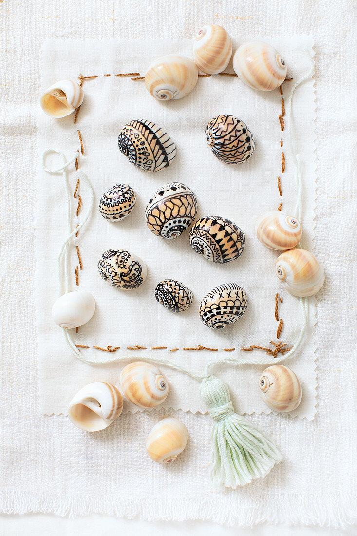 Seashells painted with patterns in black on embroidered fabric