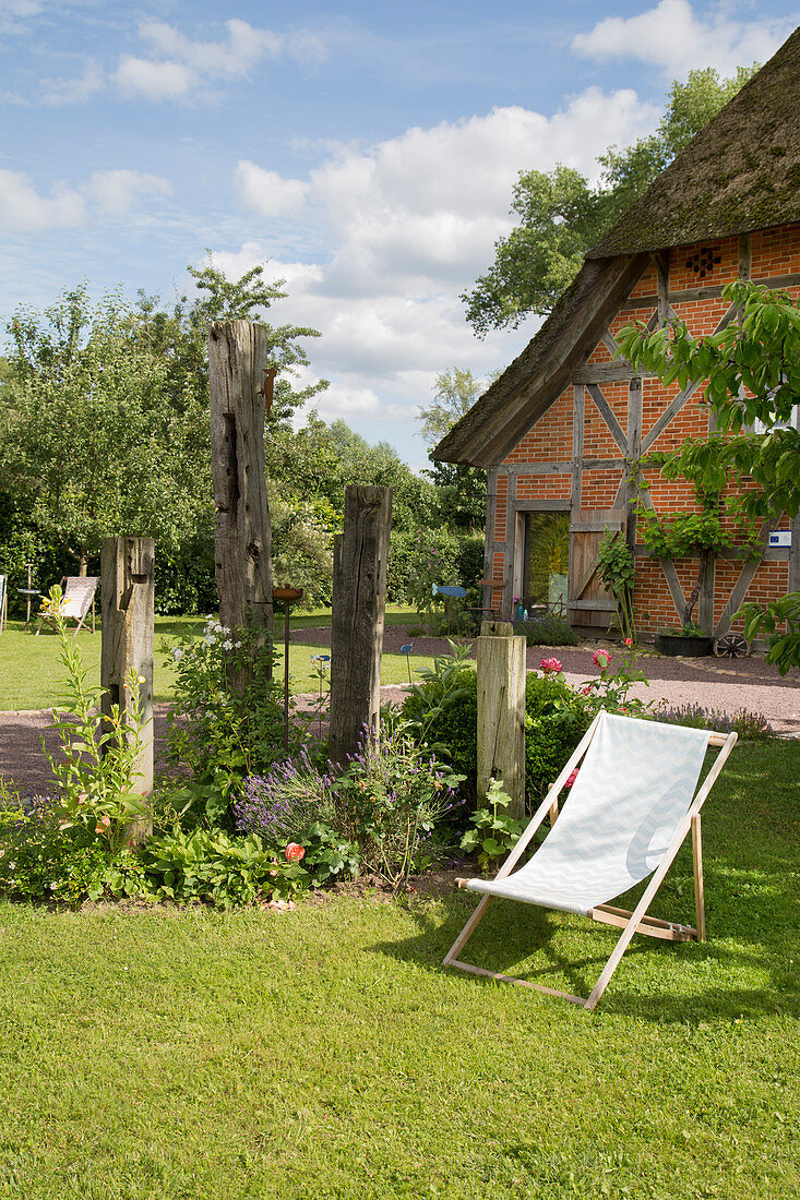 Deckchair in summer garden with thatched house in background