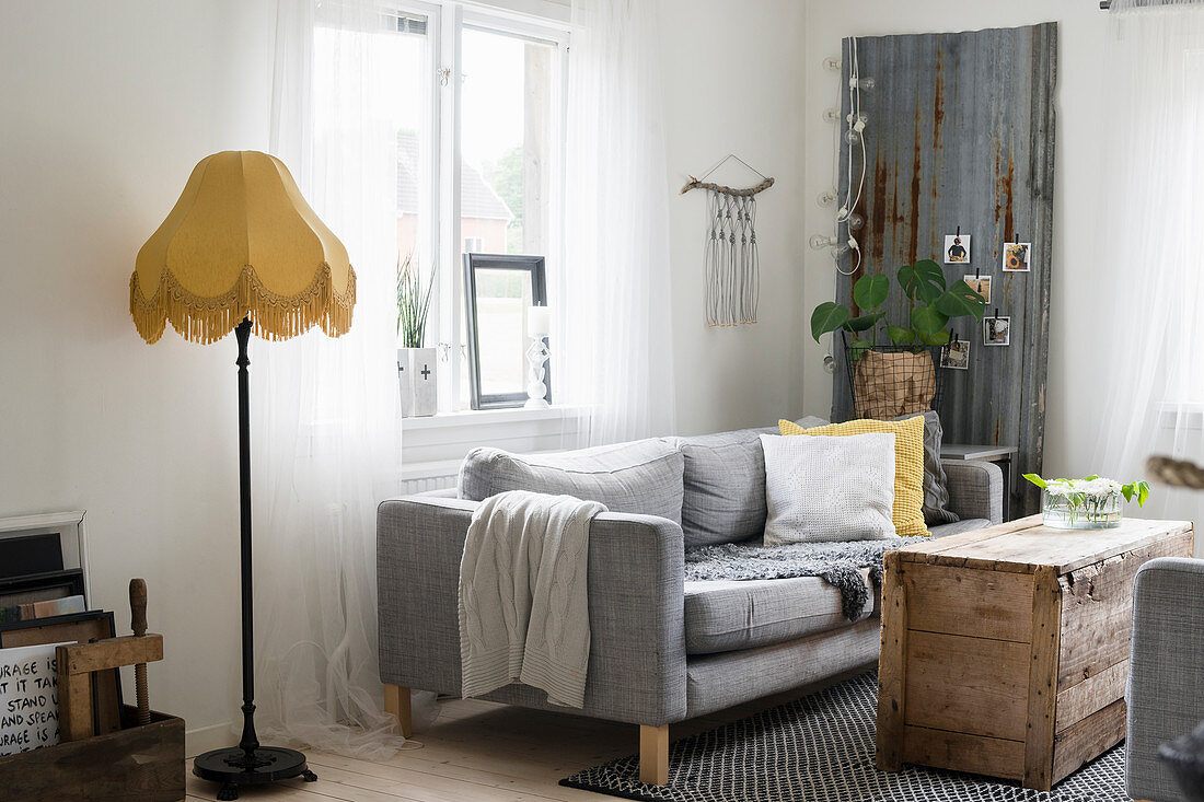 Graues Sofa und Holzkiste als Couchtisch im rustikalen Wohnzimmer