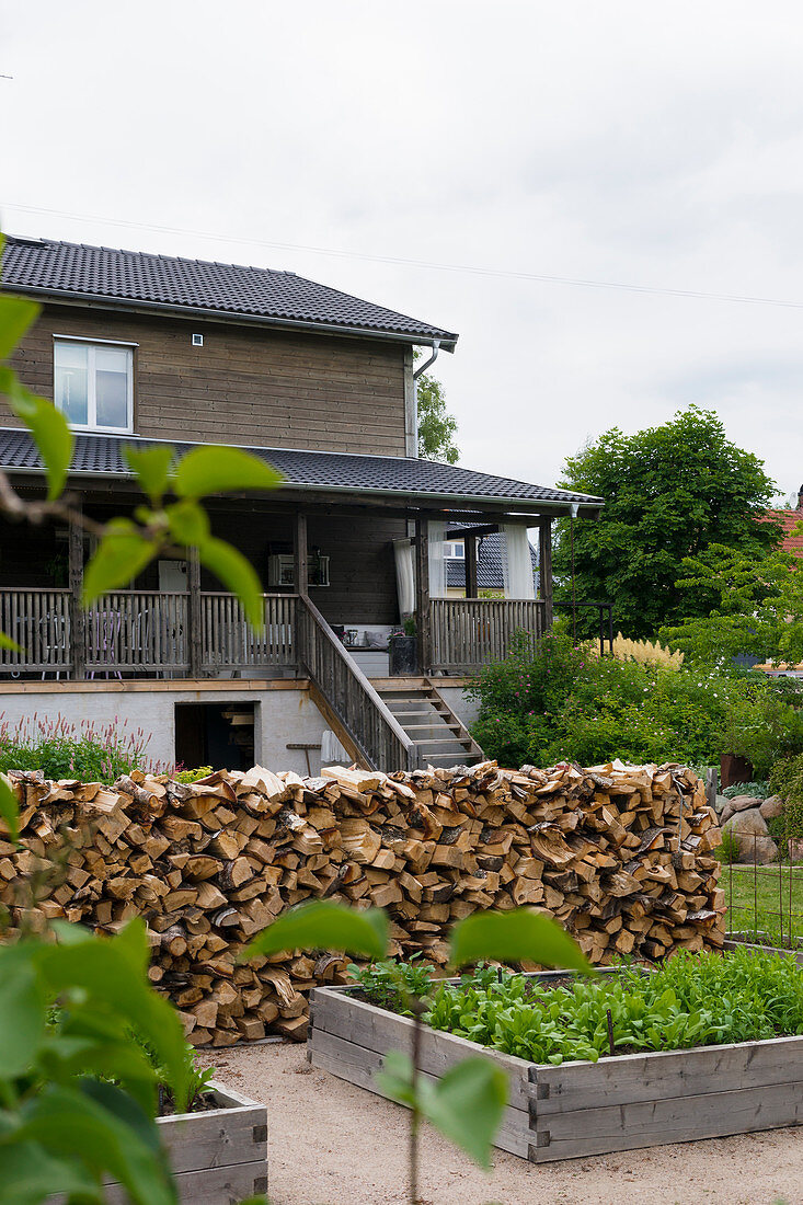 Raised beds and stacked firewood in garden of wooden house