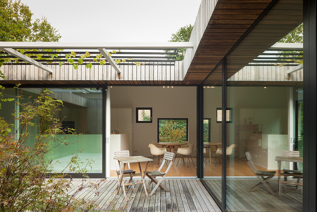 Terrace with wooden deck and view into open-plan living room