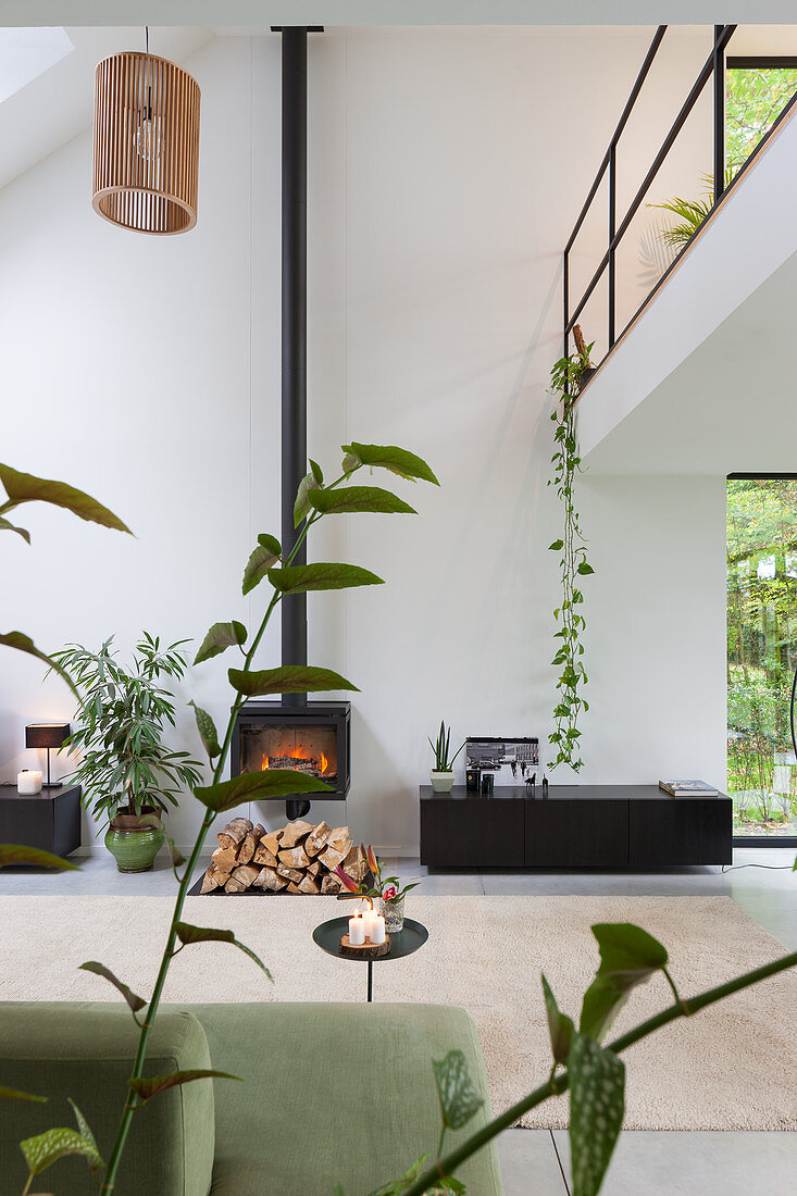 Log-burning stove in modern, open-plan, double height interior