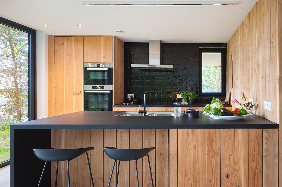 Modern kitchen with black worksurface and wooden fronts