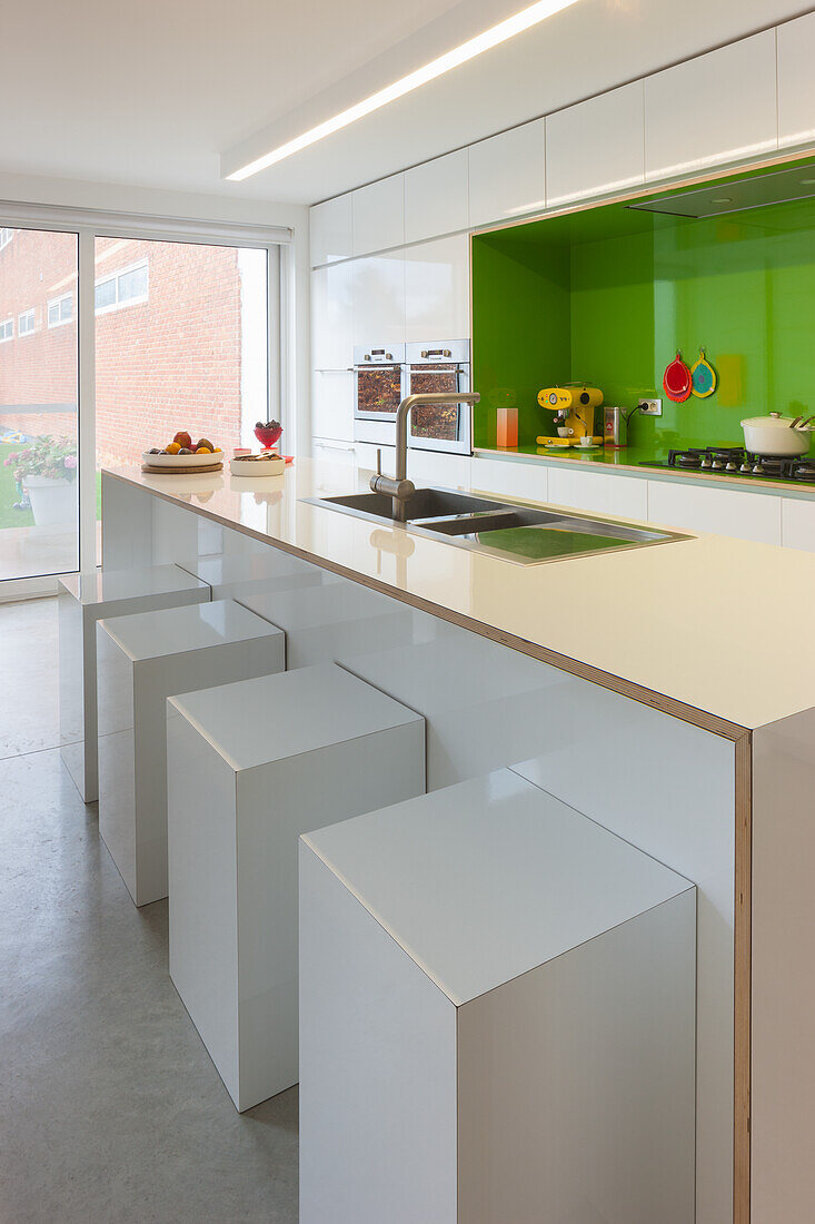 Moderne Küche mit grüner Rückwand und weißen Hochglanzfronten
