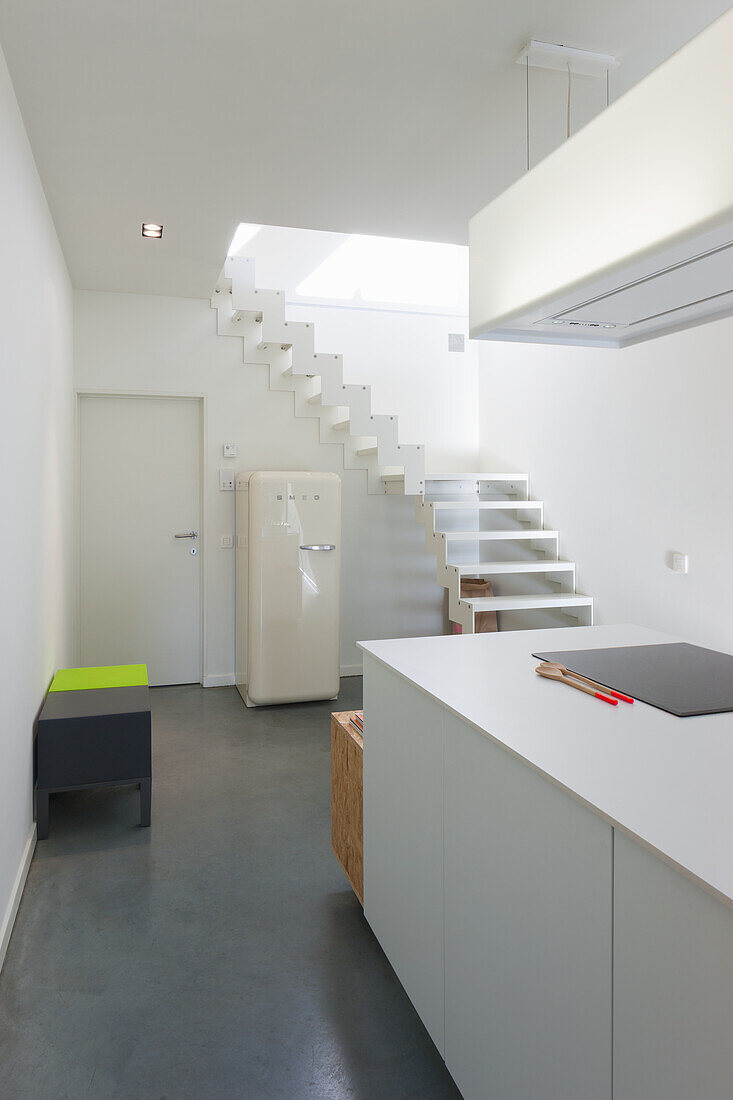 Modern kitchen with white cabinets and cantilevered staircase