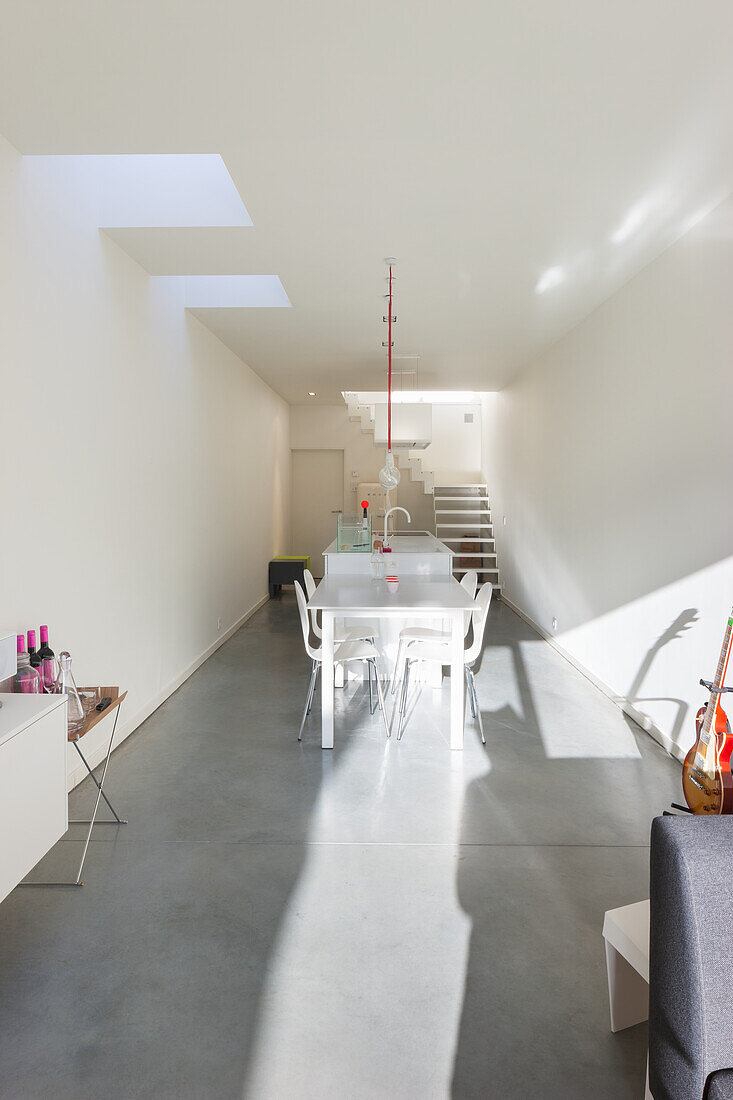 Minimalist dining area with white table and concrete floor in modern house