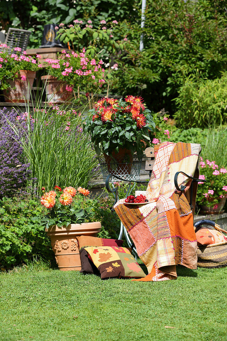 Patchworkdecke in Orangetönen auf einem Stuhl im sonnigen Garten