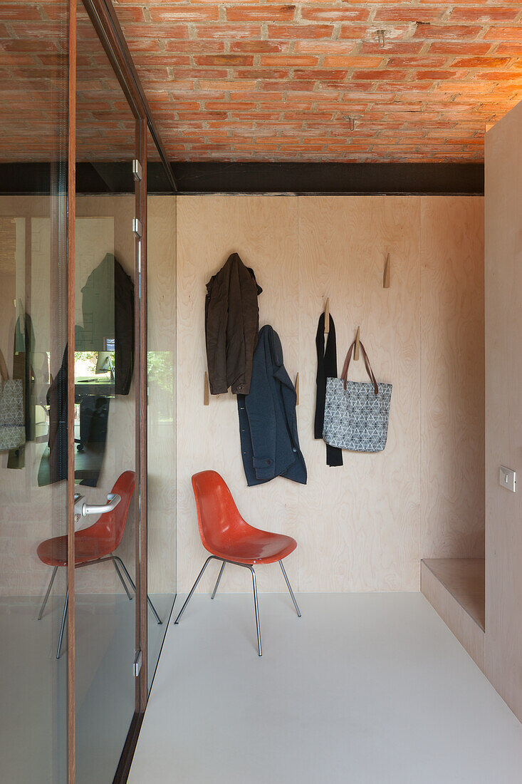 Entrance area with coat hooks, brick ceiling and red chair