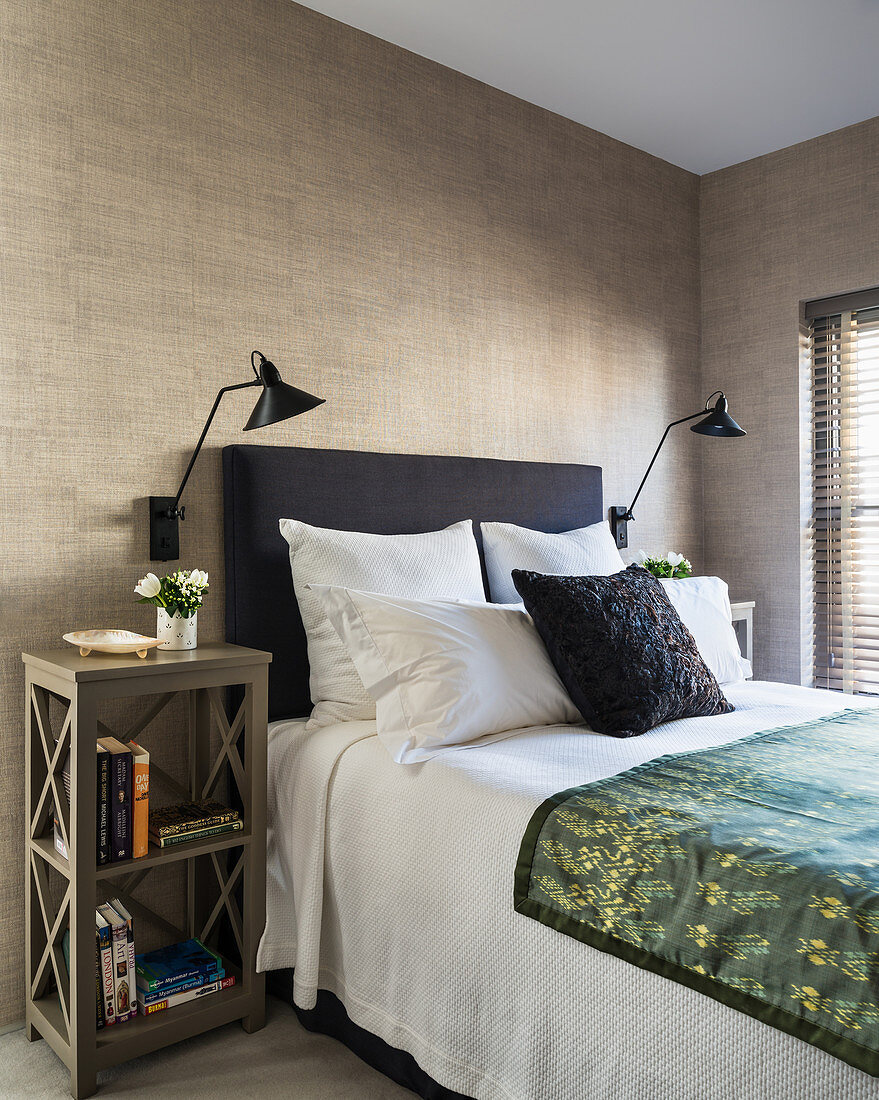 Bed with headboard against grey-brown wall in elegant bedroom