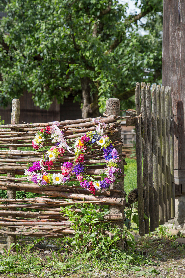 House number made from wreaths of flowers hung on wattle fence