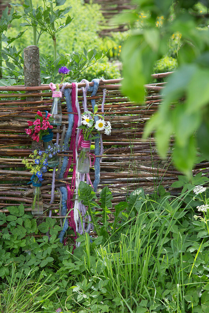 Posies in bottles hung from wattle fence