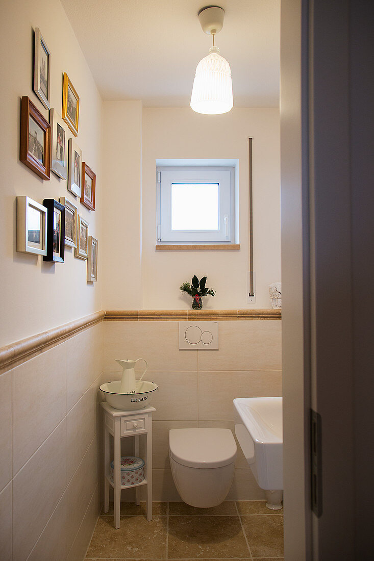Gallery of pictures on wall and half-height tiling in small bathroom