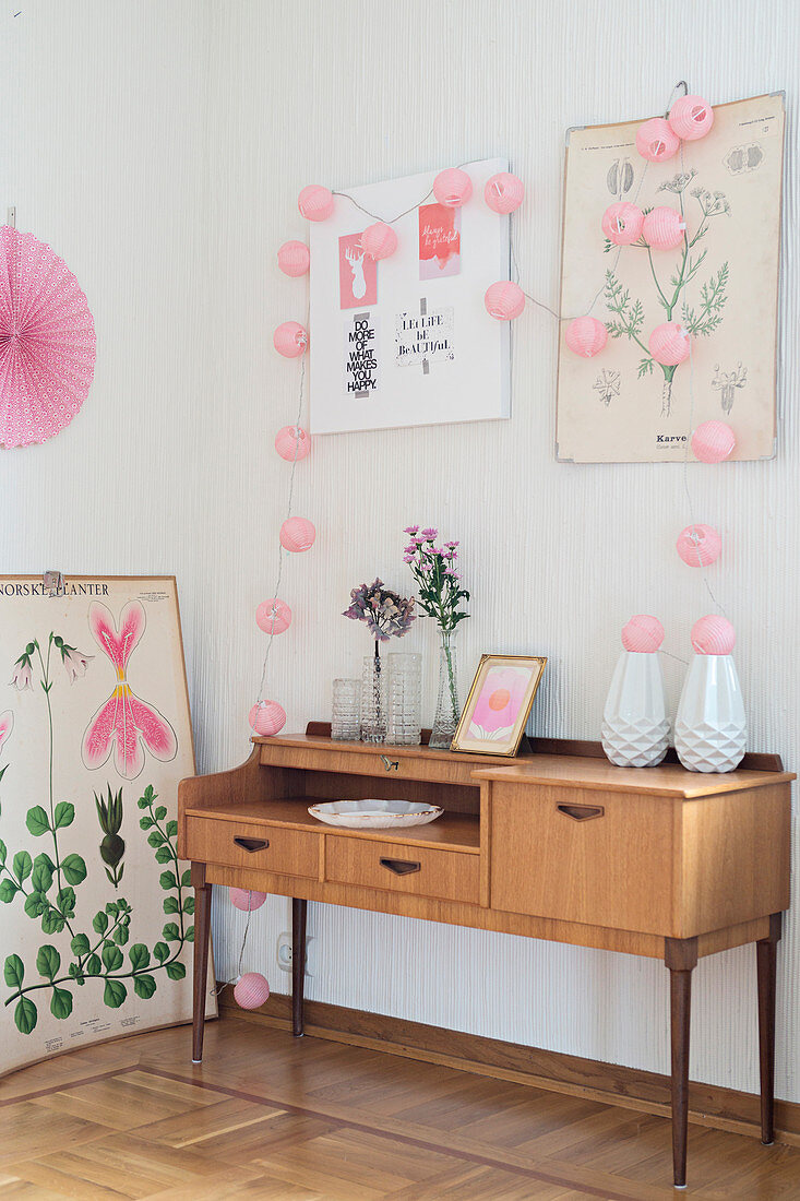 Pink decorations and botanical illustrations on and around old sideboard